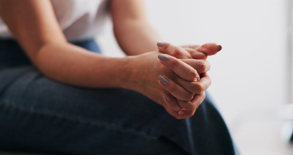 A woman clasping her hands nervously